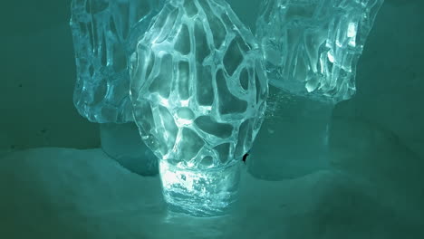 Glowing-Shiny-Ice-Crystal-Carved-Green-Morel-Mushroom-Sculptures-at-Snow-Village,-Lapland,-Finland,-Tilt-Up
