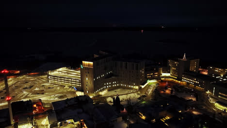 Drone-shot-circling-the-illuminated-Central-hospital-of-Vaasa,-night-in-Finland