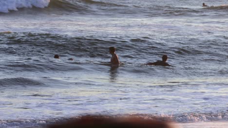 People-Swimming-on-Waves-at-Sunset,-Slow-Motion