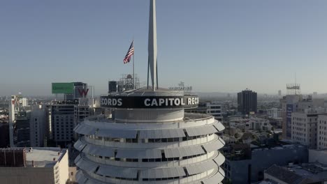 Aerial-View,-Top-of-Capitol-Records-Tower-Building-and-American-National-Flag,-Hollywood,-Los-Angeles-CA-USA