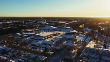 Aerial-drone-view-over-the-Raksila-district-towards-the-Ouluhalli-sport-arena,-winter-sunrise-in-Oulu,-Finland