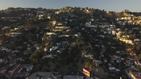Aerial-View-of-Hollywood-Hills-Above-Sunset-Boulevard-on-Golden-Hour-Sunlight,-Revealing-Tilt-Up-Drone-Shot