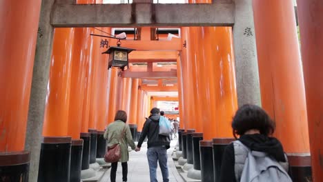 Japanese-tourist-couple-walking-through-the-red-shinto-shrines-torries-in-Kyoto-Japan