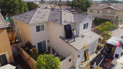 Arbeiter-Stapelt-An-Einem-Sonnigen-Tag-Solarmodule-Auf-Dem-Dach-Eines-Modernen-Hauses-In-Los-Angeles,-Kalifornien