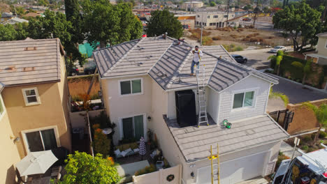 Arbeiter-Klettern-An-Einem-Sonnigen-Tag-über-Eine-Leiter-Auf-Das-Dach-Eines-Modernen-Hauses-In-Los-Angeles,-Um-Sonnenkollektoren-Zu-Installieren,-Kalifornien