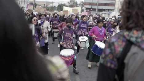 In-Lila-Gekleidete-Frauen-Spielen-Trommeln-Und-Marschieren-Während-Der-Protestaktion-Zum-Internationalen-Frauentag-In-Quito,-Ecuador