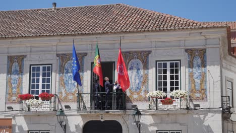 People-raise-Cascais-flag-on-City-Hall,-handheld-slow-motion