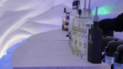 Blick-Auf-Die-Solide-Eisbar-Und-Eine-Auswahl-An-Wodkaflaschen-Und-Dekantern-Für-Heißgetränke,-Schneedorfhotel,-Handaufnahme