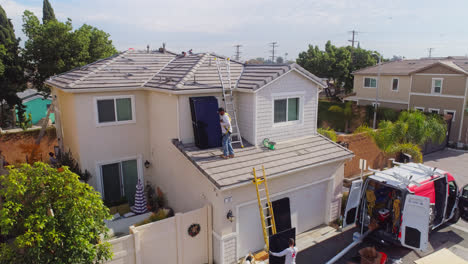 Arbeiter-Stapelt-An-Einem-Sonnigen-Tag-Solarmodule-Auf-Dem-Dach-Eines-Modernen-Hauses-In-Los-Angeles,-Kalifornien