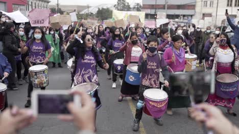 People-are-recording-a-group-of-women-who-are-playing-drums-while-they-march-during-the-protest-in-the-International-Women's-day-in-Quito,-Ecuador