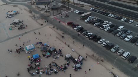 Aerial-View-of-Family-Gatherings-on-Huntington-State-Beach,-California-USA-and-Twilight-Traffic-on-Pacific-Coast-Highway,-Drone-Shot