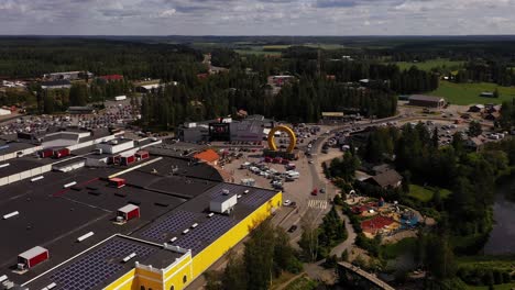 Aerial-view-away-from-the-horseshoe-statue-at-the-Keskisen-kylakauppa-department-store-in-Tuuri,-Finland---pull-back,-drone-shot