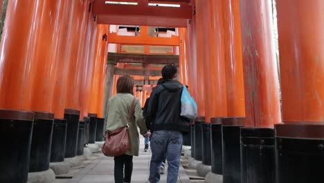 Pareja-De-Turistas-Japoneses-Caminando-Por-Los-Santuarios-Sintoístas-Rojos-En-Kioto,-Japón.