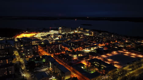 Aerial-view-approaching-the-illuminated-Central-hospital-of-Vaasa,-winter-dusk-in-Finland