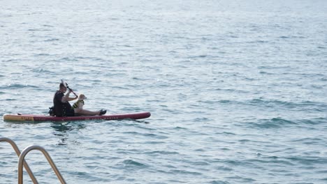 Man-paddleboard-with-dog-in-lap