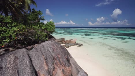 Drone-Flying-Over-Granite-Boulders-Revealing-Lady-In-Swimsuit,-Anse-Source-d'Argent,-Seychelles