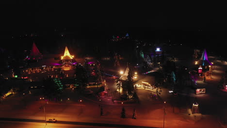 Aerial-View-of-Magical-Enchanted-Colours-of-Santa-Claus-Village-at-Night,-Finland,-Panning-Shot