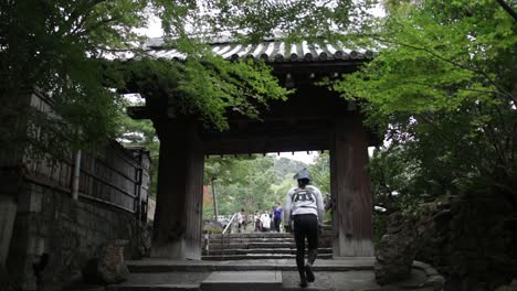 Japanese-guy-walking-up-the-stairs-in-Kyoto-at-a-wooden-gate