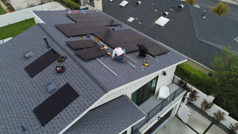 Aerial-orbit-of-Solar-panel-installation-with-workers-on-the-roof-of-a-large-residential-home
