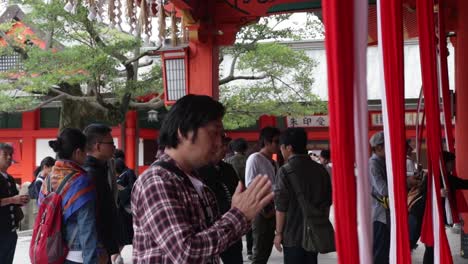 Hombre-Japonés-Local-Orando-En-El-Templo-Tocando-Las-Campanas-Tradicionales-Japonesas
