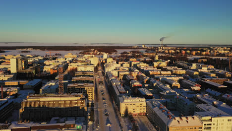 Aerial-view-of-the-sunlit,-Oulu-city-skyline,-winter-morning,-in-Finland---circling,-drone-shot