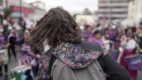 Eine-Frau-Lächelt-Und-Tanzt,-Während-Sie-Eine-Gruppe-Lila-Gekleideter-Frauen-Anführt,-Die-Trommeln-Spielen,-Während-Sie-Während-Des-Protestes-Zum-Internationalen-Frauentag-In-Quito,-Ecuador,-Marschieren