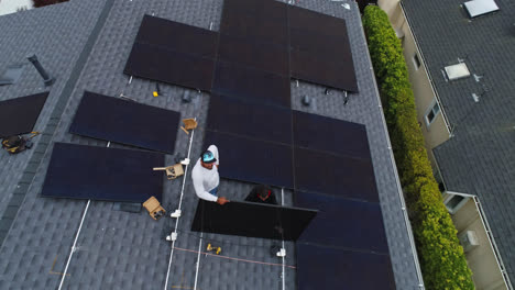Bird's-eye-view-of-male-workers-installing-solar-panels-on-house-roof
