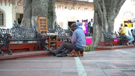 Schuhputzer-Eines-Alten-Mannes-Auf-Einem-Platz-In-Taxco,-Mexiko,-Authentische-Landschaft,-Zeitlupe