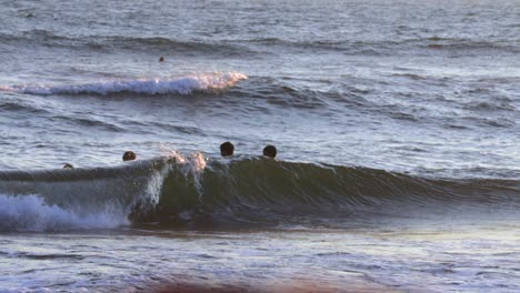 Kids-Having-Fun-in-Ocean-Waves-Breaking-on-Beach-at-Sunset,-Slow-Motion