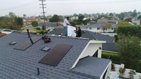 Two-workers-install-solar-panels-on-roof-of-residential-home