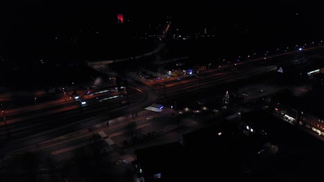 Aerial-view-away-from-a-city-railway-station,-dark,-fall-evening---pull-back,-drone-shot