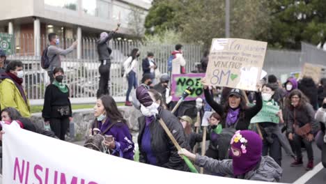 A-group-of-women-are-jumping-and-singing-while-holding-signs-with-phrases-during-the-protest-in-the-International-Women's-day-in-Quito,-Ecuador