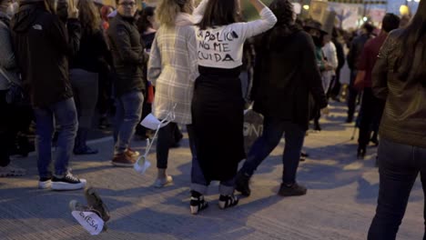 A-woman-is-holding-up-a-sign-with-a-message-and-also-wearing-a-shirt-with-a-phrase-dedicated-to-the-police-during-march-in-the-International-Women's-day