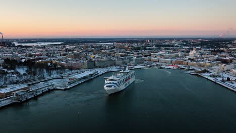 Aerial-view-of-the-Silja-line-cruise-liner-leaving-Helsinki,-during-winter-sunset---circling,-drone-shot