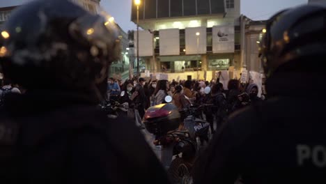 Policías-Con-Cascos-Puestos-Están-Parados-Frente-A-Un-Grupo-De-Mujeres-Que-Marchan-Durante-Una-Protesta-En-El-Día-Internacional-De-La-Mujer-En-Quito,-Ecuador.