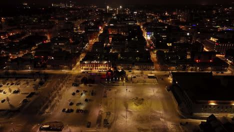 Aerial-view-overlooking-the-night-lit-market-square-of-Oulu,-winter-in-Finland