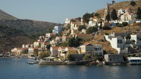 Tracking-aerial-shot-of-the-colorful-harbour-of-Ano-Symi,-First-Angle
