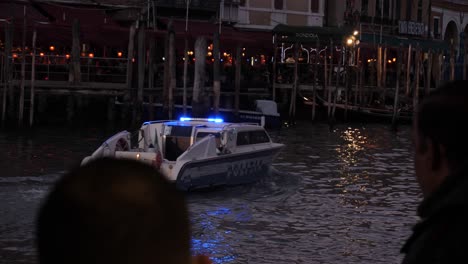 Police-boat-with-blue-lights-on-going-on-the-canal-near-Rialto-Bridge-at-dusk-in-Venice