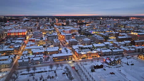 Aerial-view-overlooking-the-illuminated-cityscape-of-Oulu,-winter-evening-in-Finland