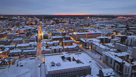 Aerial-overview-of-snowy-downtown-Oulu,-winter-sunset-in-Ostrobothnia,-Finland