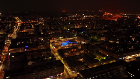 Aerial-rising-shot-of-a-illuminated-square-in-downtown-Oulu,-winter-evening-in-Finland