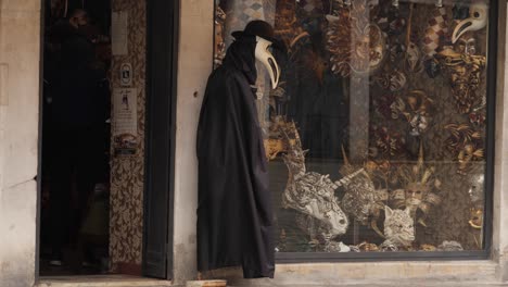 Gruselige-Venezianische-Maske-Mit-Langer-Nase-Und-Langes-Schwarzes-Kleid-An-Der-Tür-Eines-Maskenladens-In-Venedig