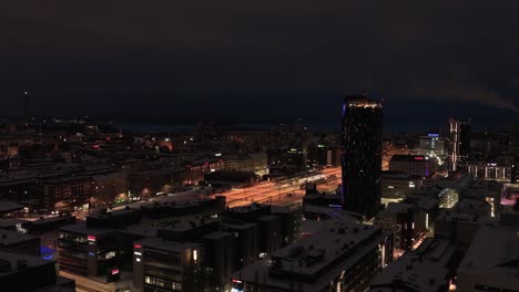 Aerial-view-tracking-the-lit-downtown-of-Tampere,-Finland,-during-a-winter-night