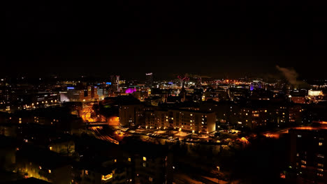 Aerial-view-toward-the-illuminated-skyline-of-Tampere-city,-winter-evening-in-Finland