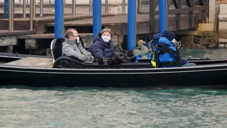 Family-sitting-in-a-gondola-wearing-protective-face-masks-one-day-after-the-cancellation-of-the-Venice-Carnival,-due-to-Coronavirus-outbreak