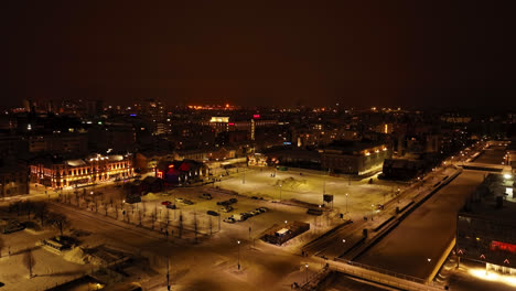 Aerial-rising-shot-in-front-of-the-snowy-market-square,-winter-night-in-Oulu,-Finland