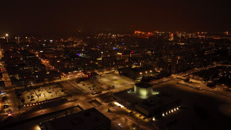 Aerial-tracking-shot-of-the-illuminated-market-square-and-downtown-Oulu,-misty-winter-evening-in-Finland