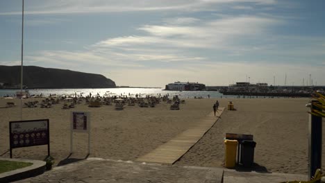 Sandy-beach-of-Los-Cristianos,-Harbour-with-ferry-in-background