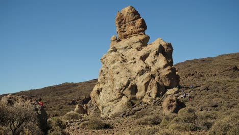 Hikers-walking-around-a-lone-rock-formation-in-Teide-National-Park