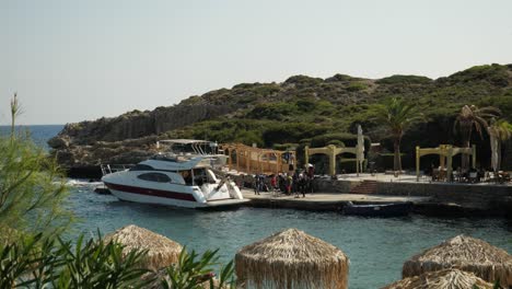 View-on-Kallithea-Beach,-A-yacht-moored-waiting-for-scuba-divers-dressing-up,-Parasols-in-foreground